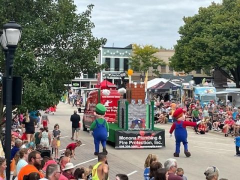 Community event featuring Monona Plumbing and Fire Protection with mascots and fire safety displays.