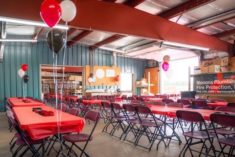 Event space decorated with balloons, tables, and chairs for a plumbing and fire protection company c.