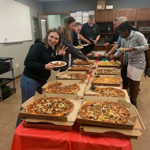 Pizza delivery event with multiple varieties of pizza on a red tablecloth.