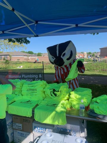 Monona Plumbing and Fire Protection booth with safety gear and promotional shirts.