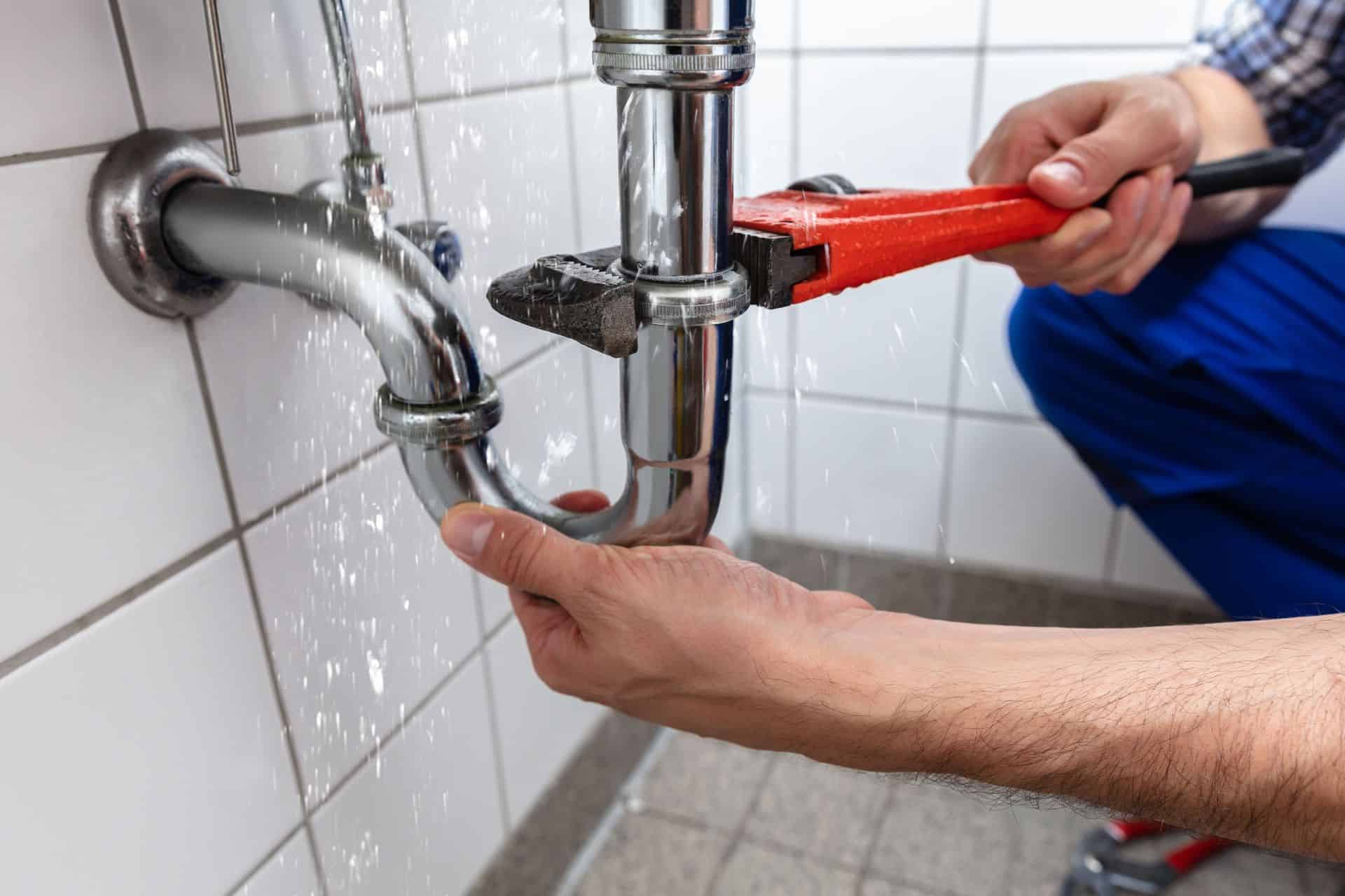 Technician repairing plumbing pipe with a wrench in a commercial building.