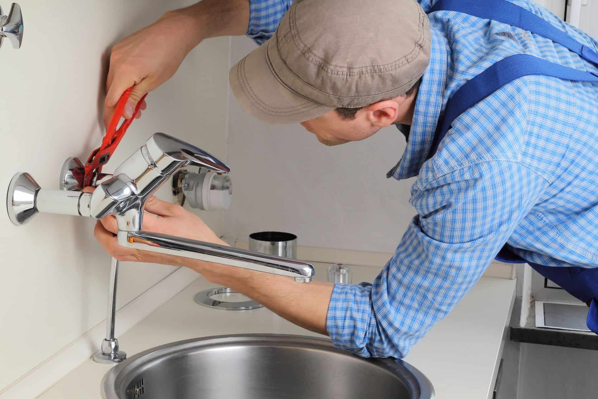 Professional plumber fixing a faucet with tools for plumbing repair and fire protection systems.