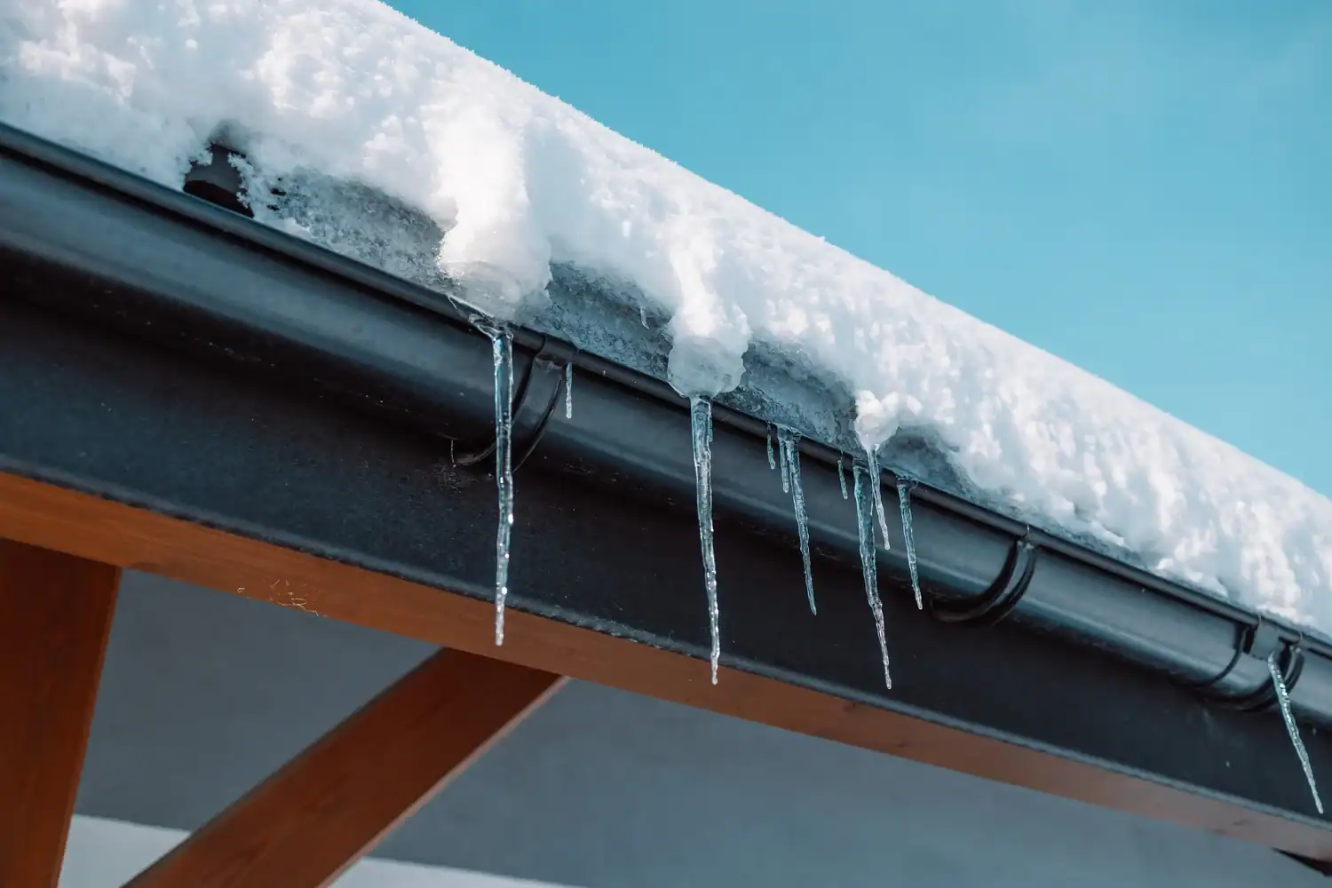 Plumbing and fire protection pipes with icicles on snowy roof.