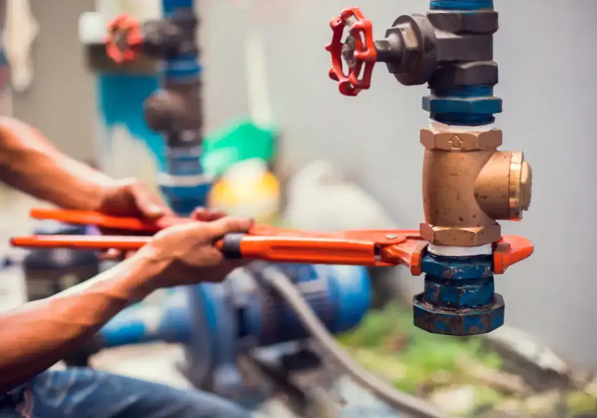 Plumbing technician working on fire protection system with valves and pipes.
