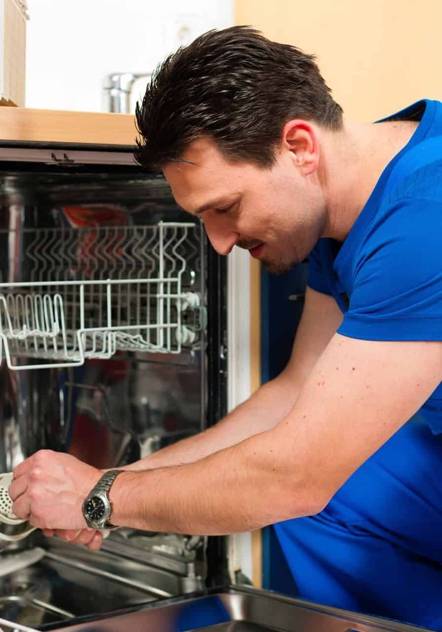 Technician inspecting dishwasher plumbing system.