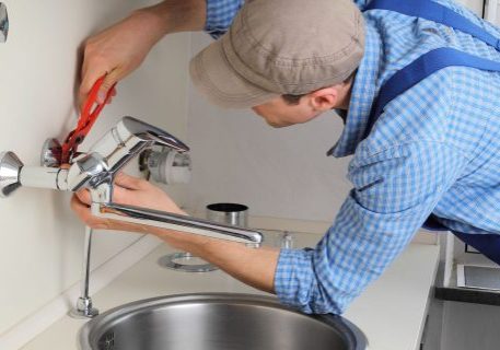Professional plumber fixing a faucet with tools for plumbing repair and fire protection systems.