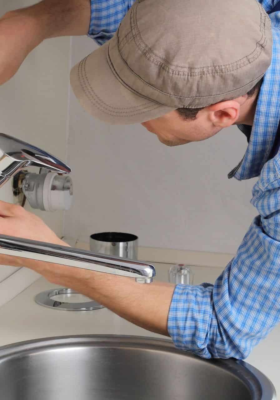 Professional plumber fixing a faucet with tools for plumbing repair and fire protection systems.