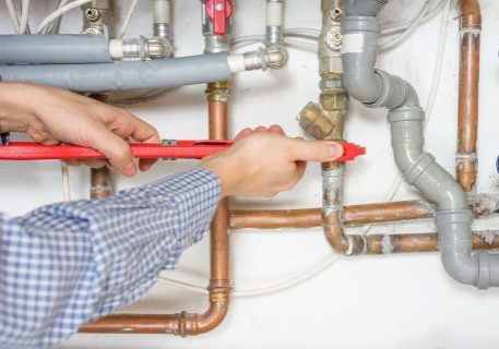 Technician inspecting plumbing and fire protection pipes in a building.