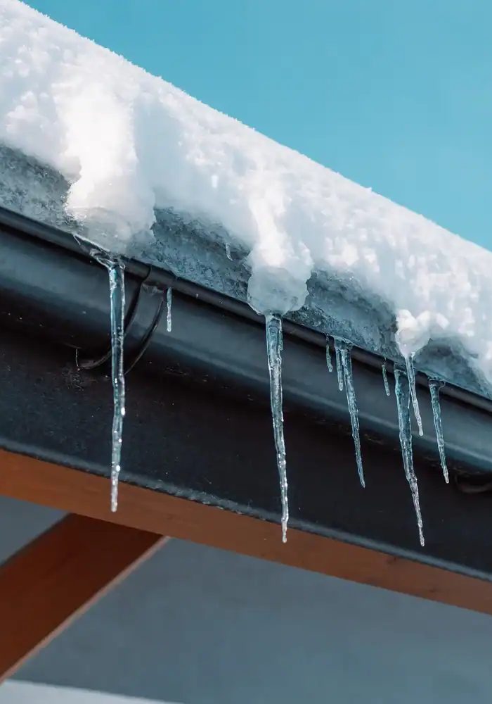 Plumbing and fire protection pipes with icicles on snowy roof.